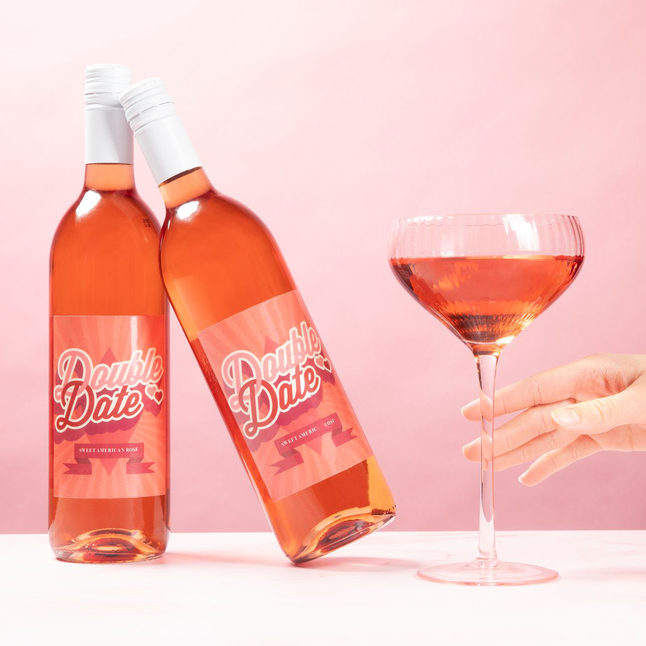 Two bottles of Double Date Sweet Rosé with a full glass.